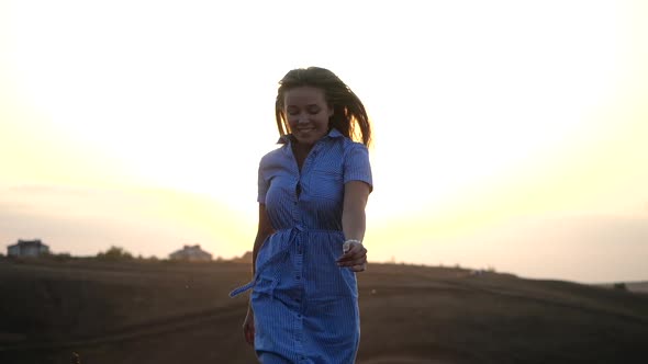 Happy Young Feminine Girl Runs on a Background of Sunny Sunset. Her Long Silky Hair Flutters in the alt
