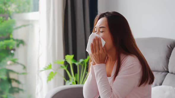 Young asian women with allergies feeling unwell using tissues and sneezing