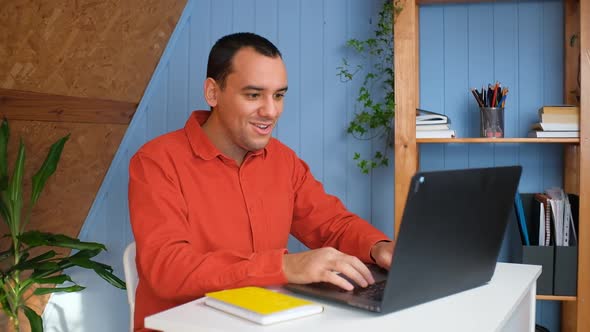Young Business Man Gets Successful News Sits at Table with Laptop in Home Office alt
