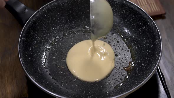 Pouring pancake dough over a heated pan. Close up