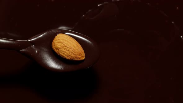Melted Liquid Premium Dark Chocolate and Almond Rotating Process of Making Sweet Desserts with Nuts alt
