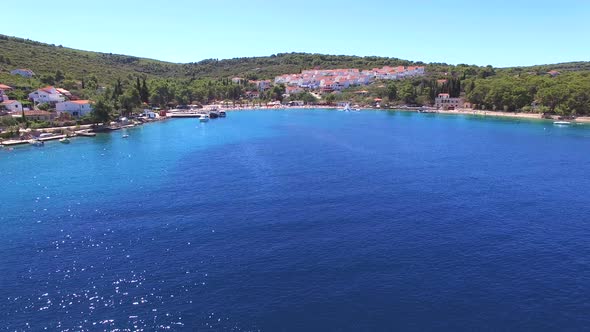 Aerial view of clear blue bay with apartments on hill and public beach, Croatia alt
