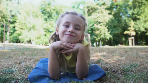 Beautiful Small Girl Lying on Blanket in Park, Spending Leisure Time, Resting