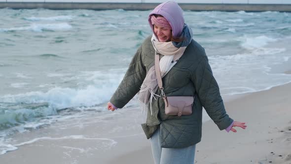 Woman in Warm Clothes Walks Near the Sea Waters on the Winter Beach