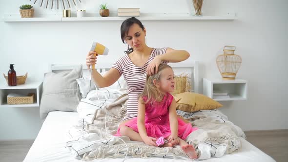 Mother Drying Hair of Kid Girl with a Hair Dryer alt