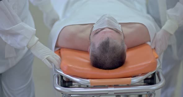 Doctors Carry a Sick Man on a Stretcher Along the Hospital Corridor alt