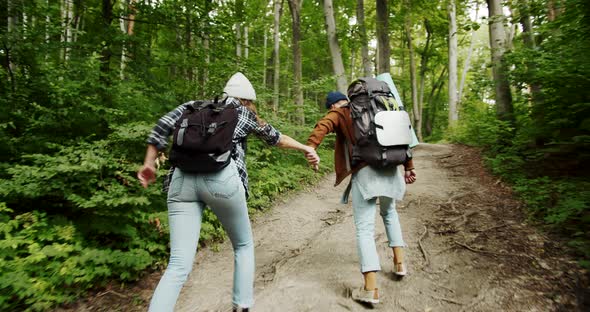 Couple of Tourists with Backpacks Running