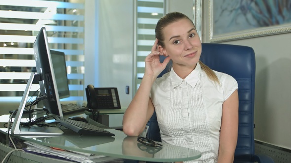 Portrait of woman sitting in busy creative office looking at camera