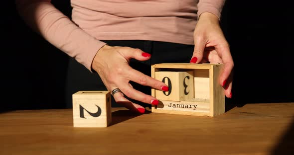 Woman hand change, sets the date on the wooden calendar on 01 Janyuary alt