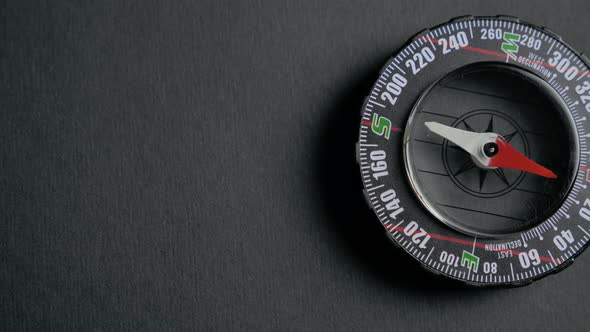 a Modern Compass Lying on a Black Desk with a Red Arrow That Shows the Direction alt