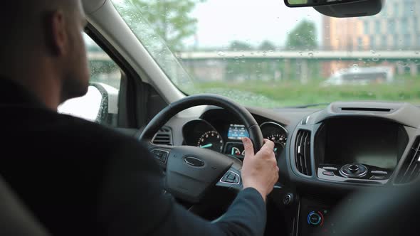 Man Drives a Car Along the Road in the City During the Rain alt