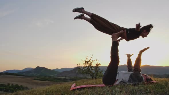 Couple Practice Complex Exercises of Yoga at Dusk on the Hilltop alt