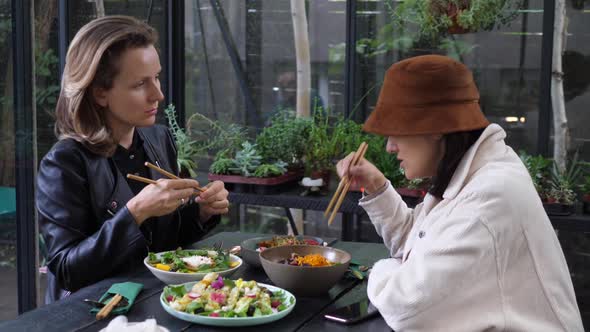 Two Girlfriends Having Conversation Over Their Healthy Vegan Lunch in Oriental Style . Enjoying alt