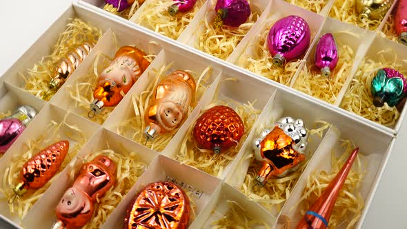 Vintage glass Christmas toys lie in boxes on decorative straw