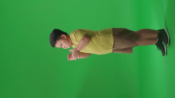 Side View Of Asian Little Boy Clapping His Hands In The Green Screen Studio alt
