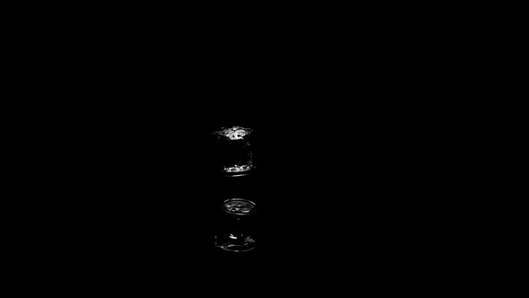 A Glass Of Water Falls , Splashes Spill Over The Surface On A Black Background