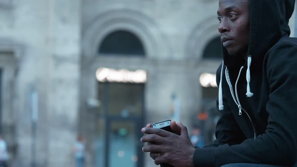 Thoughtful sad lonely black african man alone in the street alt