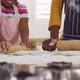 Happy african american mother and daughter rolling dough in kitchen