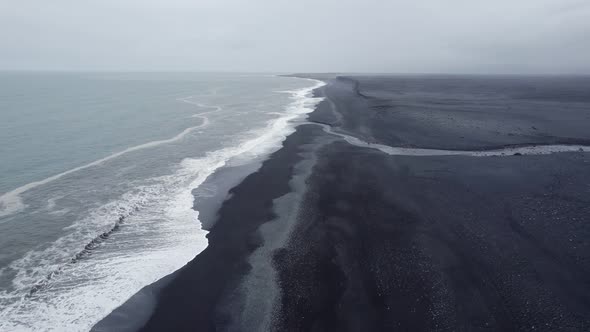 Flying over the southern coastline of Iceland as the Atlantic Ocean waves break on the black sand alt