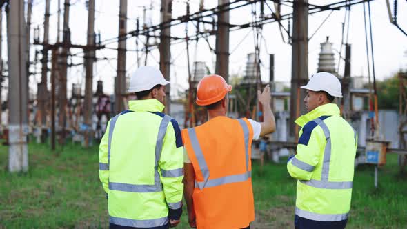 Three Engineer Discussing the Work Plan Standing With Electricity Towers