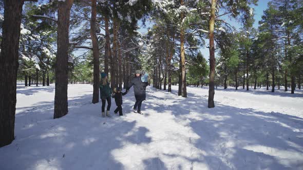 Young Family with Two Kids Walks in Winter Park with Snow alt