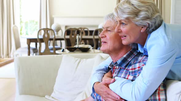 Senior couple watching tv together in living room alt