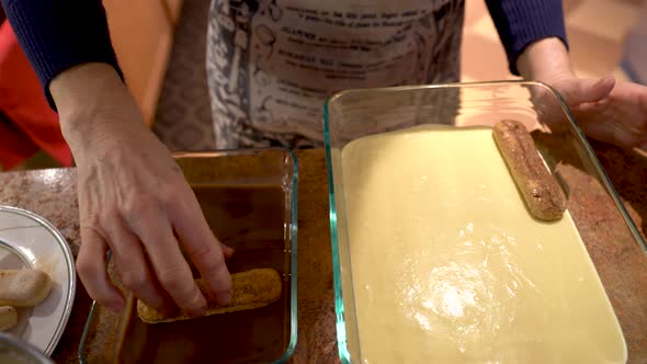 Closeup of chef putting second layer of lady fingers on top of the sabayon for tiramisu. alt