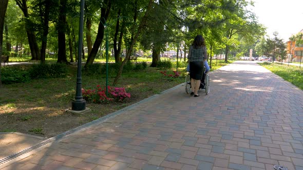 Man on Wheelchair Walking with His Wife Outdoors