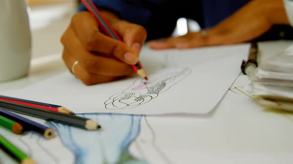 Close-up of black female fashion designer drawing sketches of dress at dining table 4k alt