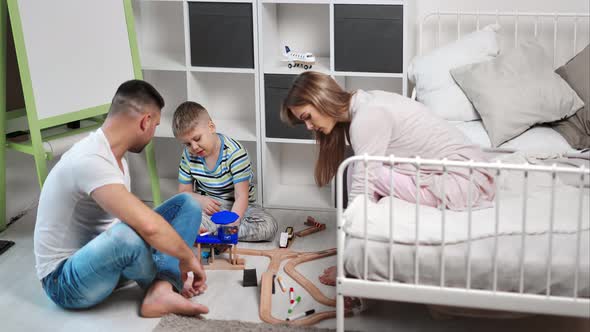 Enthusiastic Family Mother Father and Son Playing Toy Car Road Together at Comfortable Bedroom alt