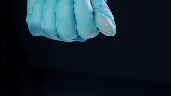 Woman's Hand in a Medical Glove Clenched Into Fist Unclenches Palm Pills Capsules in Gel Shell on alt