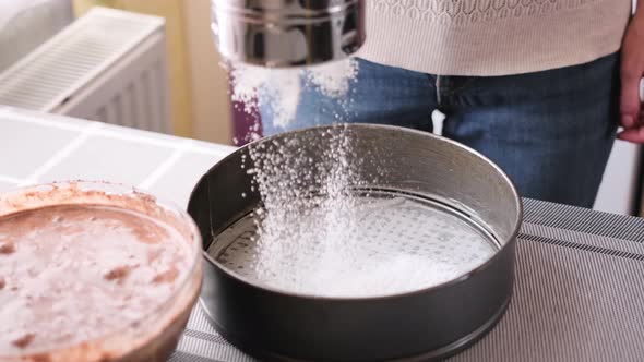 Closeup of Bakery Concept  Woman Flouring a Baking Dish for a Cake alt