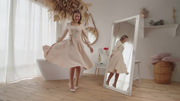 Happy Charming Female in New Dress Spinning Around in Front Mirror Indoors alt