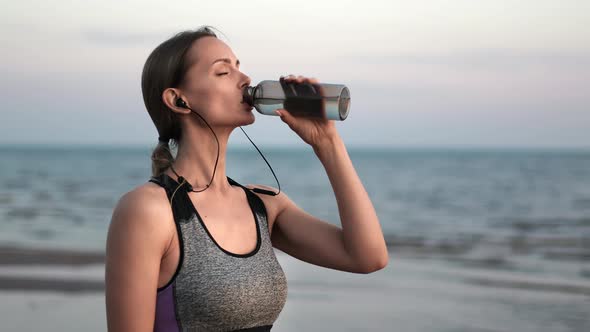 Smiling Sport Woman Drinking Pure Water Jogging at Sunset Sea Beach Healthy Lifestyle Closeup Slowmo alt