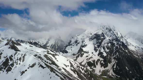 Air Flight Through Mountain Clouds Over Beautiful Snowcapped Peaks of Mountains and Glaciers alt
