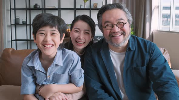 Portrait of happy Asian family spending time together on sofa in living room