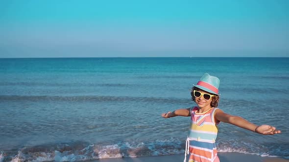 Happy Child with Open Hands against Blue Sea and Sky Background