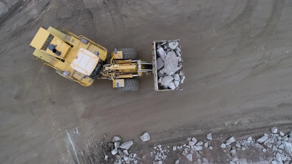 Wheel loader caterpillar drops cobblestones into quarry