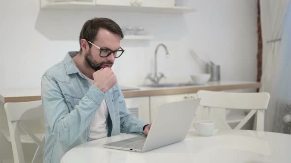 Serious Young Beard Young Man Thinking and Working on Laptop alt