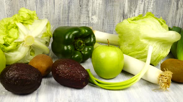 Ingredients of a fresh vitamin salad from fruits and vegetables of green color are on a table