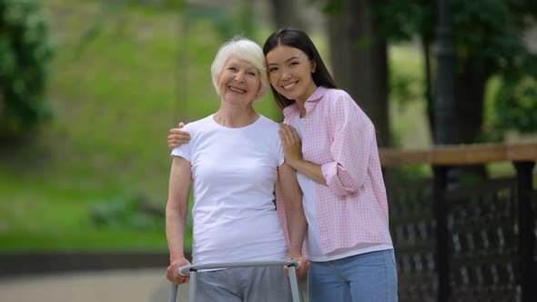 Volunteer and Disabled Old Woman Smiling Into Camera in Hospital Park, Care alt