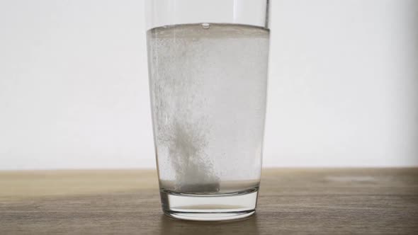 Effervescent Tablet Dissolves in a Transparent Glass with Water Closeup