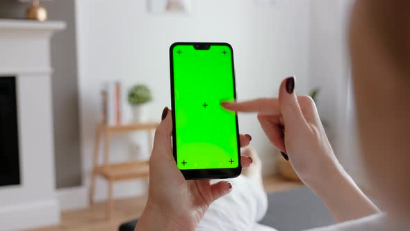 Young Female Using Smart Phone Sitting On Sofa At Home