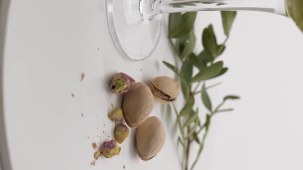Vertical video, Close-up: pistachios and chocolates near a glass of alcohol, wine alt