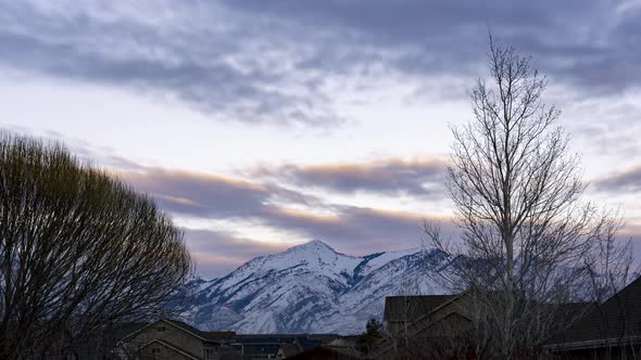 Sunset to night time lapse of snowy mountains overlooking an urbanized in the valley - static alt