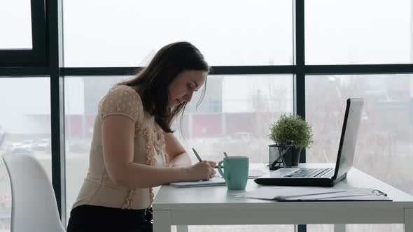Young Woman Working in Office and Taking Notes alt