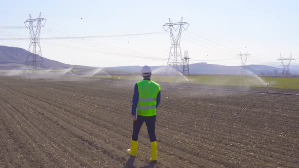Engineer walking in the field and agricultural irrigation.