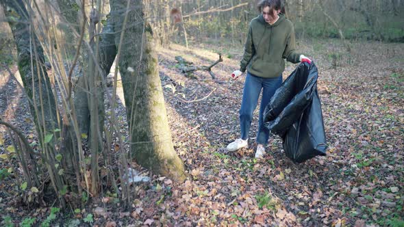 A Woman Walks Through the Woods and Removes Plastic Bottles