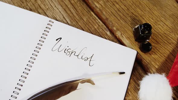 Close-up of diary, ink bottle, santa hat and quill alt
