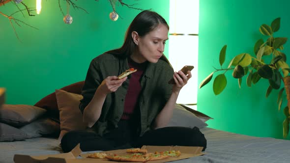 Female sitting in sofa at home and pizza browse. smartphone alt